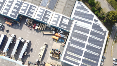 A large industrial building with multiple solar panels installed on the roof at Caps Cases, Newmarket