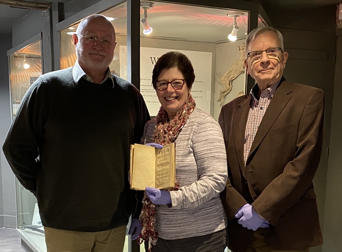 Cllr Ian Shipp with Diane Hind, Chair of the Friends of Moyse’s Hall Museum holding A Tryal of Witches, At the Assizes Held at Bury St. Edmunds for the County of Suffolk, alongside Terry O’Donoghue, Secretary and Vice-chair of the Bury Society