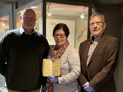 Cllr Ian Shipp is pictured with Diane Hind, Chair of the Friends of Moyse’s Hall Museum holding A Tryal of Witches, At the Assizes Held at Bury St. Edmunds for the County of Suffolk, alongside Terry O’Donoghue, Secretary and Vice-chair of the Bury Society