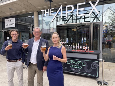 James Hulston, Regional Sales Manager for Greene King, Cllr Cliff Waterman, Leader of West Suffolk Council, and Kirsty Pollard, Centre Manager at The arc shopping centre in Bury St Edmunds toast the new mobile bar with a glass of Pilfer icon